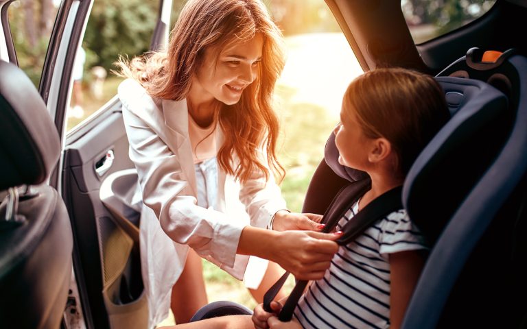 a-cute-woman-mother-put-her-daughter-in-a-car-seat-and-fastens-h