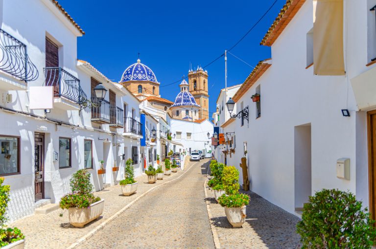 altea-old-town-narrow-street-sant-miquel-iglesia-nuestra-senora-del-consuelo-virgin-of-consol-church-typical-white-houses-buildings-and-green-bushes-in-stone-pots-altea-city-historic-centre-spain