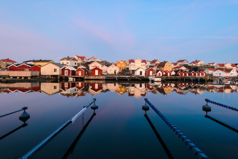 colorful-houses-reflecting-in-a-calm-harbor-on-the-west-coast-of-sweden-during-sunset