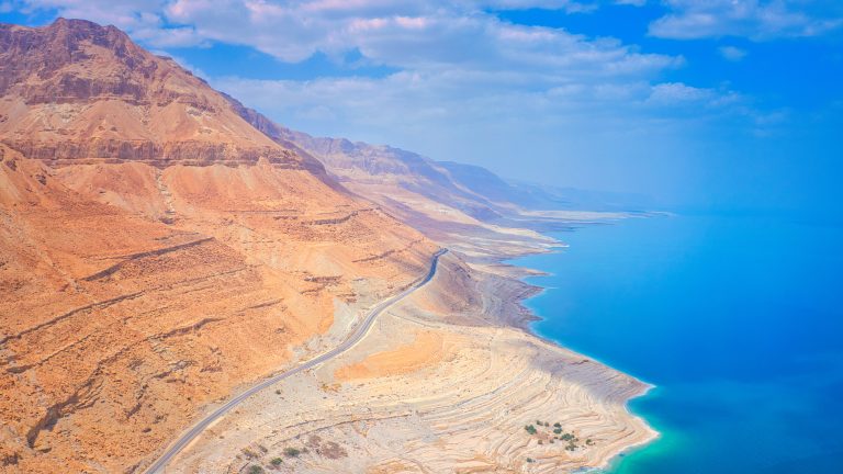 aerial-view-of-coastal-road-and-desert-mountains-along-the-dead-sea